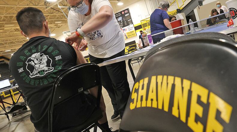 Nicole Wilson, a nurse at the Clark County Combined Health District, gives a student his COVID vaccine injection during a vaccine clinic at Shawnee High School. BILL LACKEY/STAFF