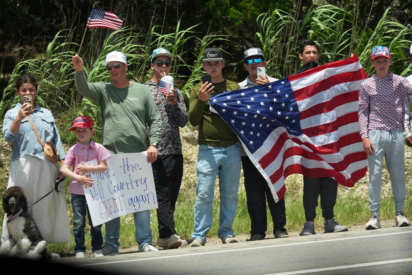 People watch as President Donald Trump and first lady Melania Trump pass in a motorcade in Kerrville, Texas, to monitor flood damage, Friday, July 11, 2025. (AP Photo/Jacquelyn Martin)