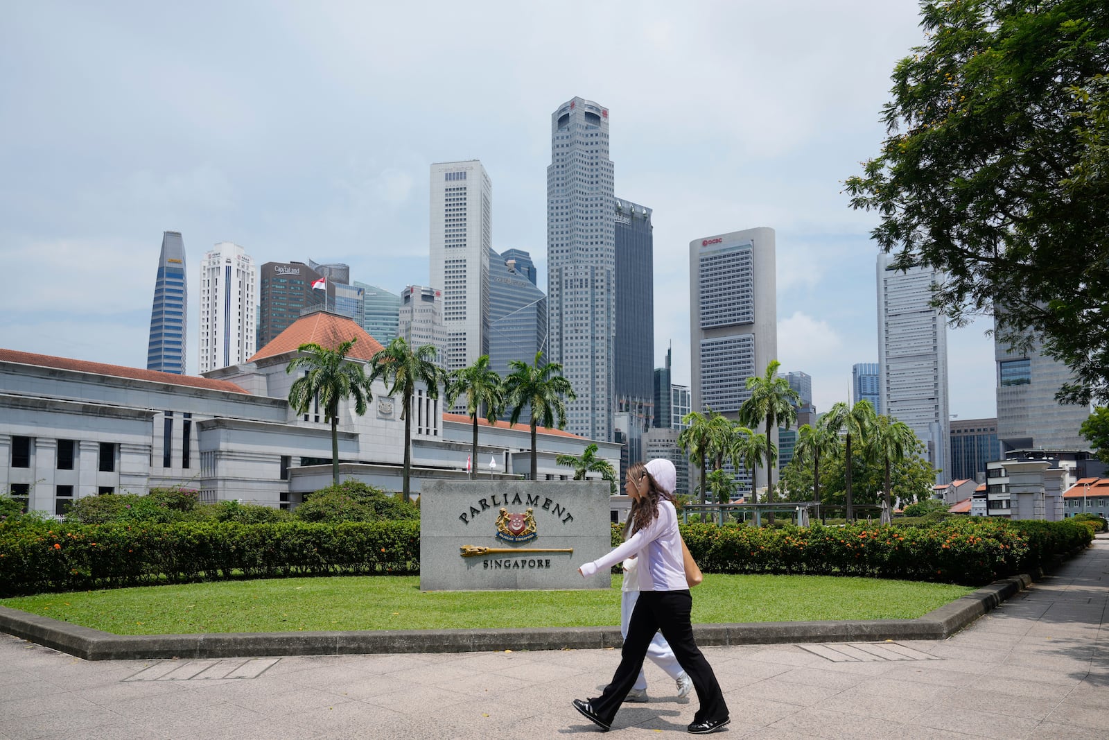 Pedestrians walk in front of the parliament building in Singapore, Friday, May 2, 2025. (AP Photo/Vincent Thian)