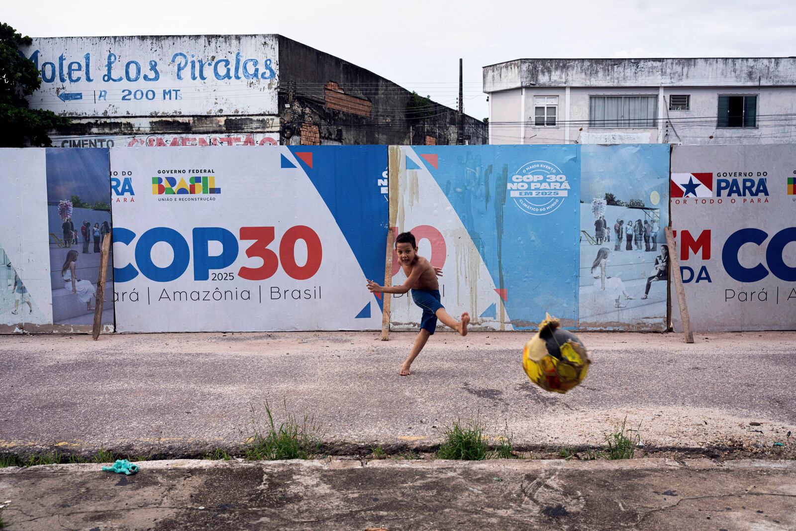 FILE - A boy kicks a soccer ball near signage for the COP30 U.N. Climate Conference in Belem, Brazil, March 23, 2025. (AP Photo/Jorge Saenz, File)