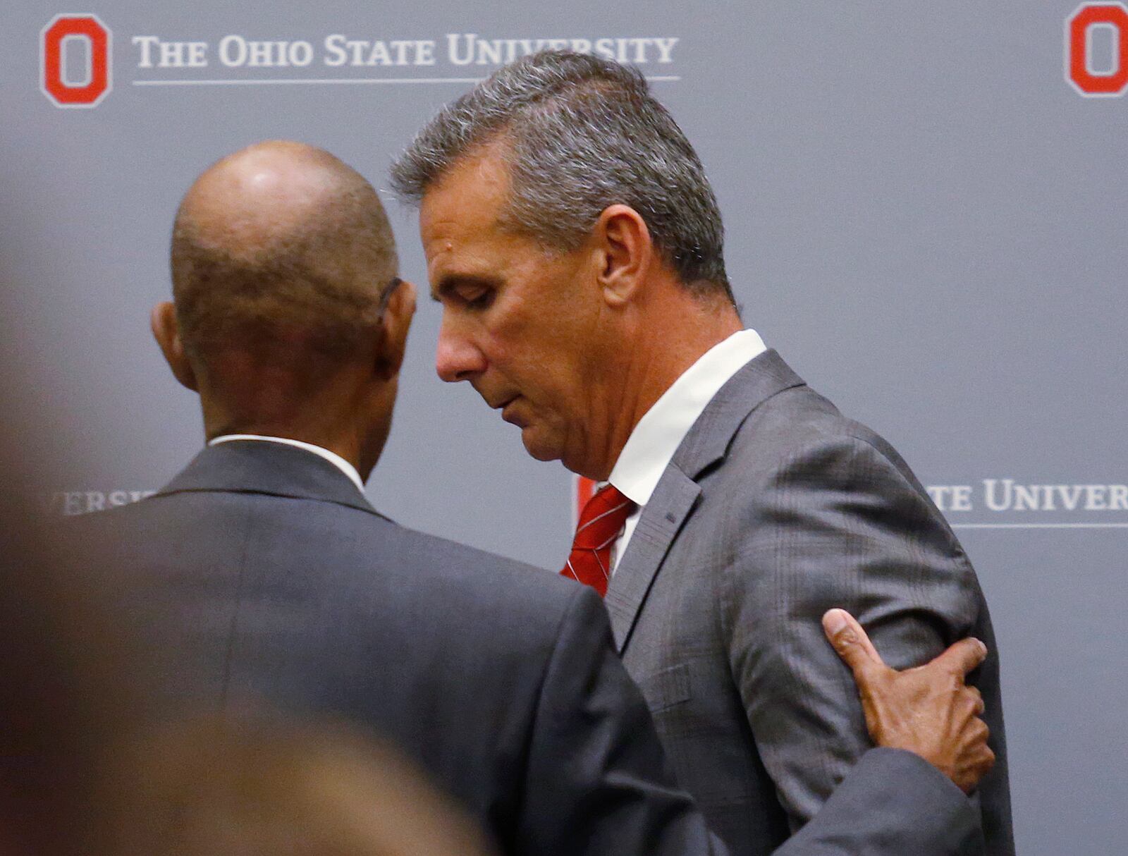 Ohio State University President Michael Drake offers words to football coach Urban Meyer, who leaves the stage following a news conference in Columbus, Ohio, Wednesday, Aug. 22, 2018. Ohio State suspended Meyer on Wednesday for three games for mishandling domestic violence accusations, punishing one of the sport’s most prominent leaders for keeping an assistant on staff for several years after the coach’s wife accused him of abuse. Athletic director Gene Smith was suspended from Aug. 31 through Sept. 16. (AP Photo/Paul Vernon)