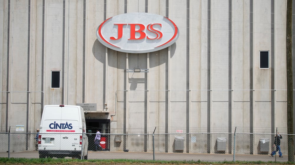 FILE - Employees walk in front of the entrance to the JBS meat processing plant, July 23, 2021, in Greeley, Colo. (AP Photo/David Zalubowski, File)