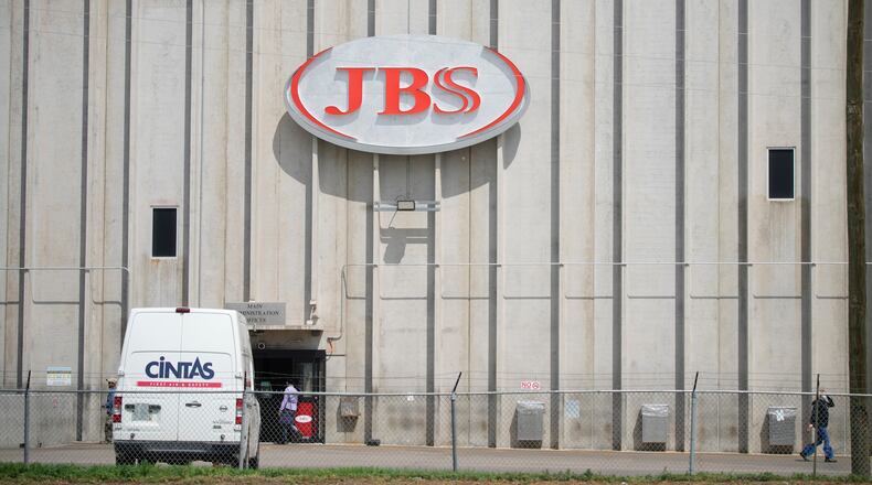 FILE - Employees walk in front of the entrance to the JBS meat processing plant, July 23, 2021, in Greeley, Colo. (AP Photo/David Zalubowski, File)