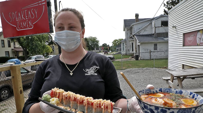 Brittany Waters delivers a customer's food on the new outdoor dinning area at Speakeasy Ramen Monday. BILL LACKEY/STAFF