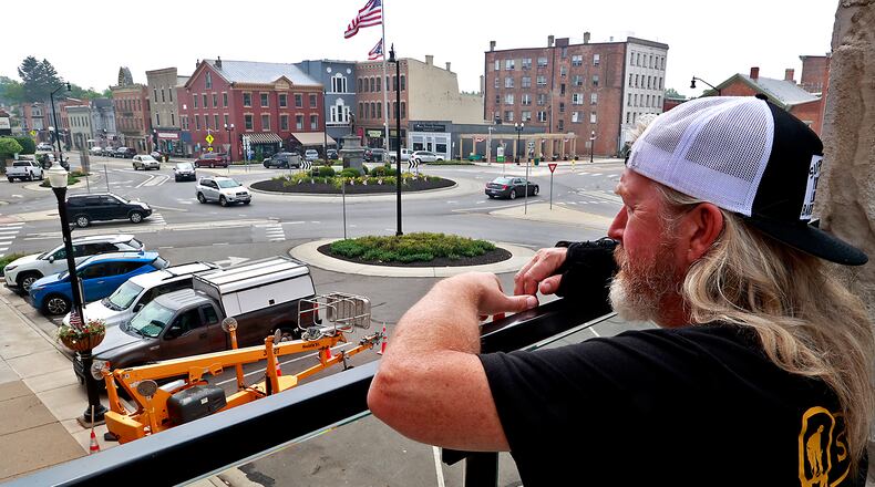 Before opening Thursday, June 29, 2023, Matt Miller, a bartender at the Urbana Brewing Co., looks out over downtown Urbana from the Brewing Co.'s roof top terrace. BILL LACKEY/STAFF