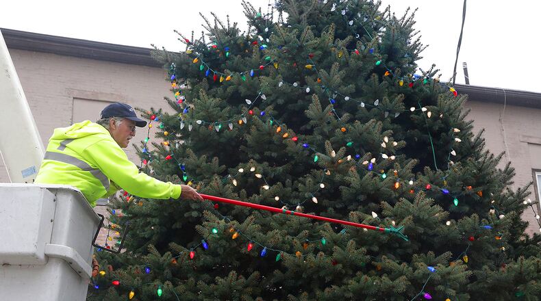 Greg Slattery hangs lights on the New Carlisle City Christmas tree Wednesday. The tree will be officially turned on during a ceremony Friday evening. BILL LACKEY/STAFF
