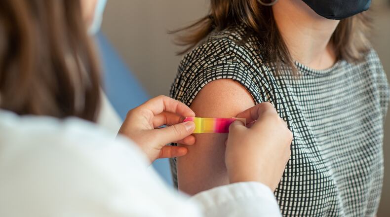 In this 2022 photo, captured inside a clinical setting, a patient shows off their bandage on the injection site where they just received an influenza vaccine. The best way to prevent seasonal flu is to get vaccinated every year, the Centers for Disease Control and Prevention says. The CDC recommends everyone 6-months of age and older get a flu vaccine every season. COURTESY OF THE CDC