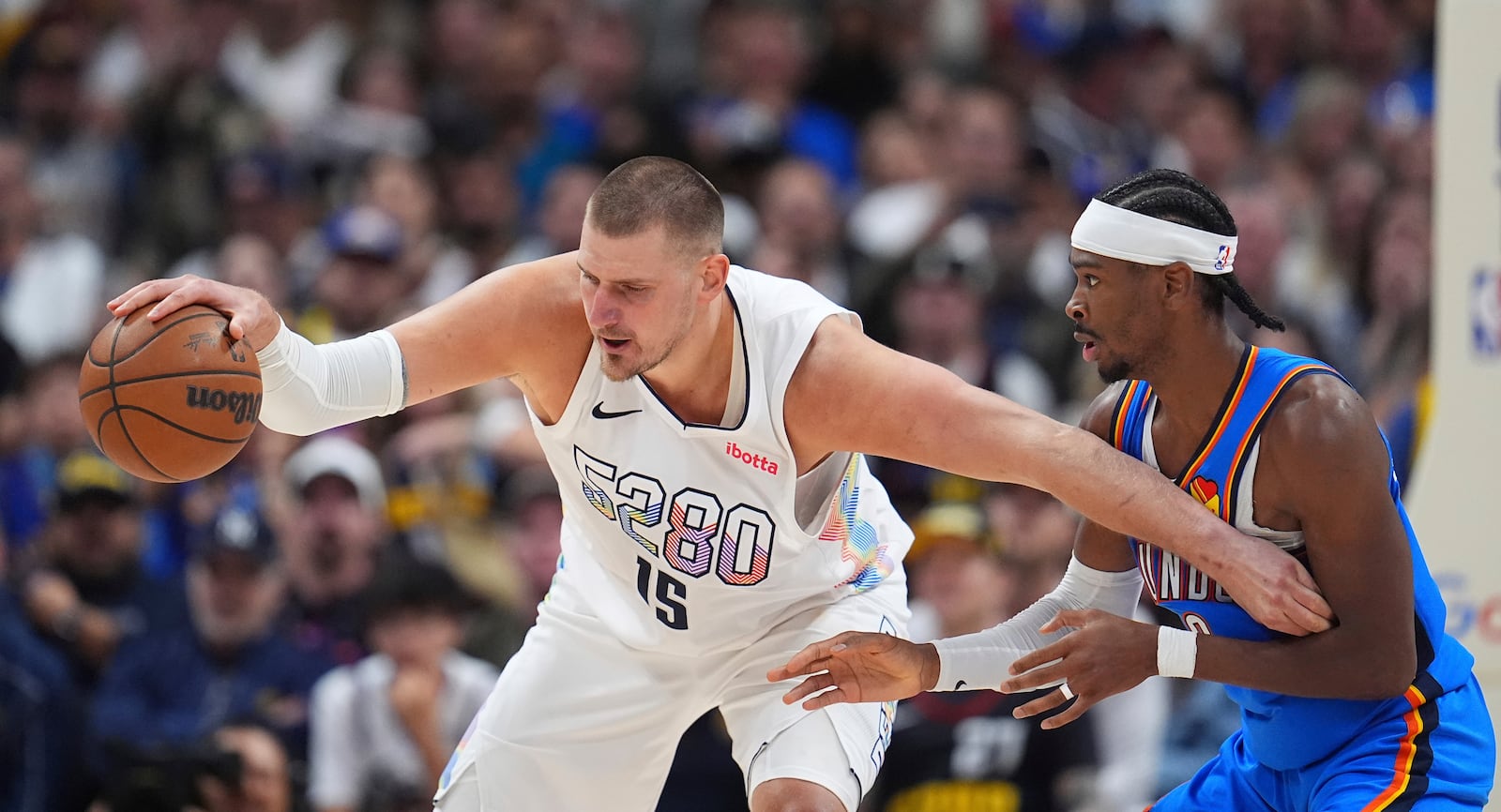 Denver Nuggets center Nikola Jokic, left, struggles to control the ball as Oklahoma City Thunder guard Shai Gilgeous-Alexander defends in the second half of Game 6 in the Western Conference semifinals of the NBA basketball playoffs Thursday, May 15, 2025, in Denver. (AP Photo/David Zalubowski)