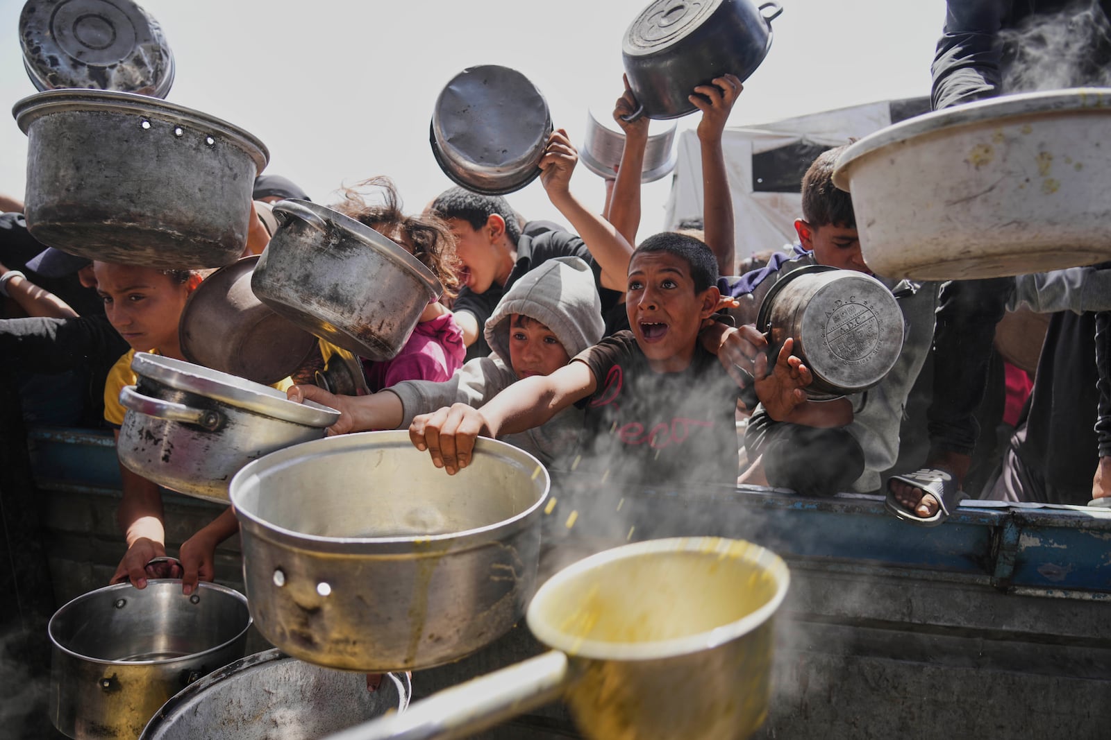 Palestinian children struggle to get donated food at a community kitchen in Khan Younis, Gaza Strip, Saturday, May 3, 2025. (AP Photo/Abdel Kareem Hana)