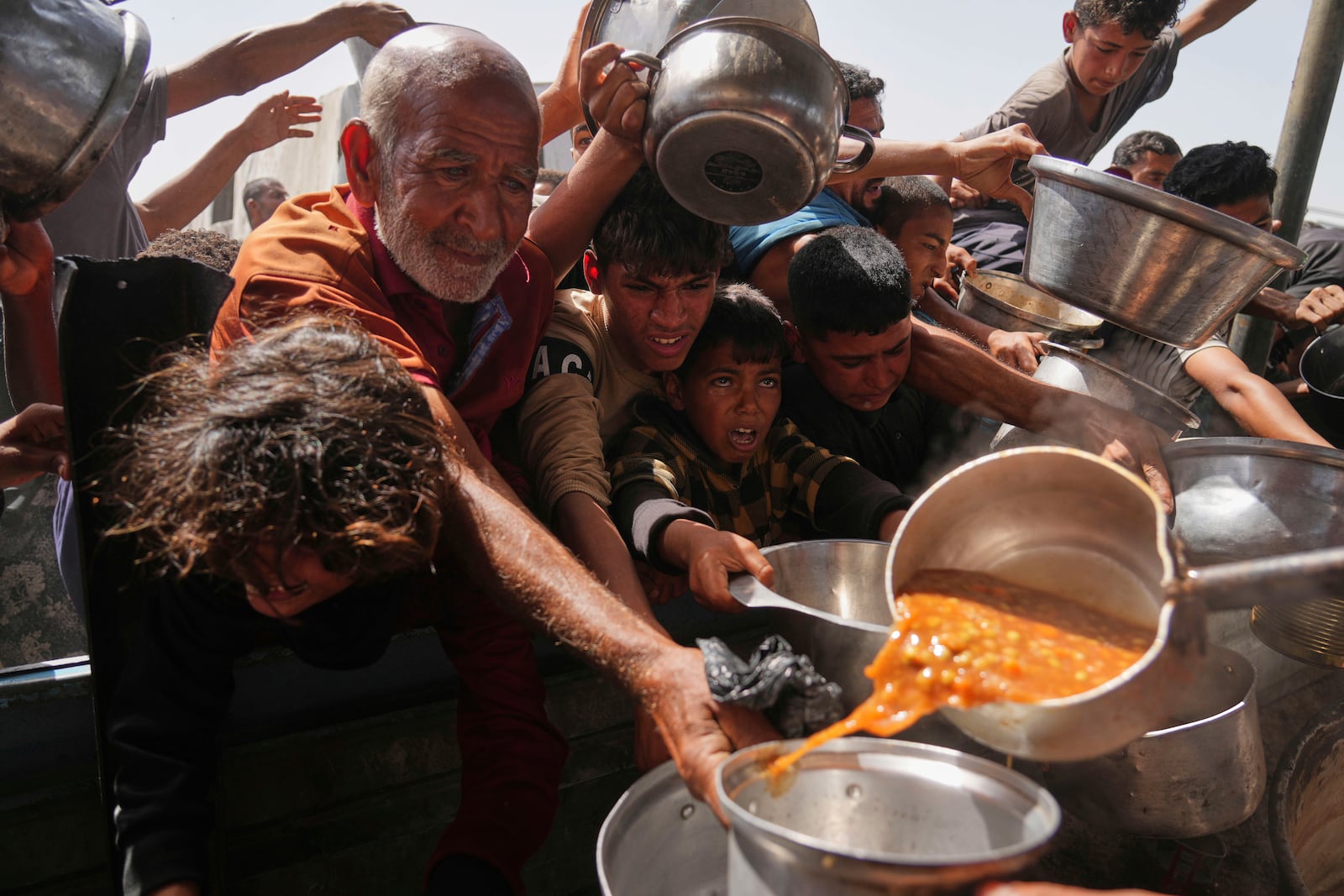 Palestinians struggle to get donated food at a community kitchen in Khan Younis, Gaza Strip, Sunday, May 11, 2025. (AP Photo/Abdel Kareem Hana)