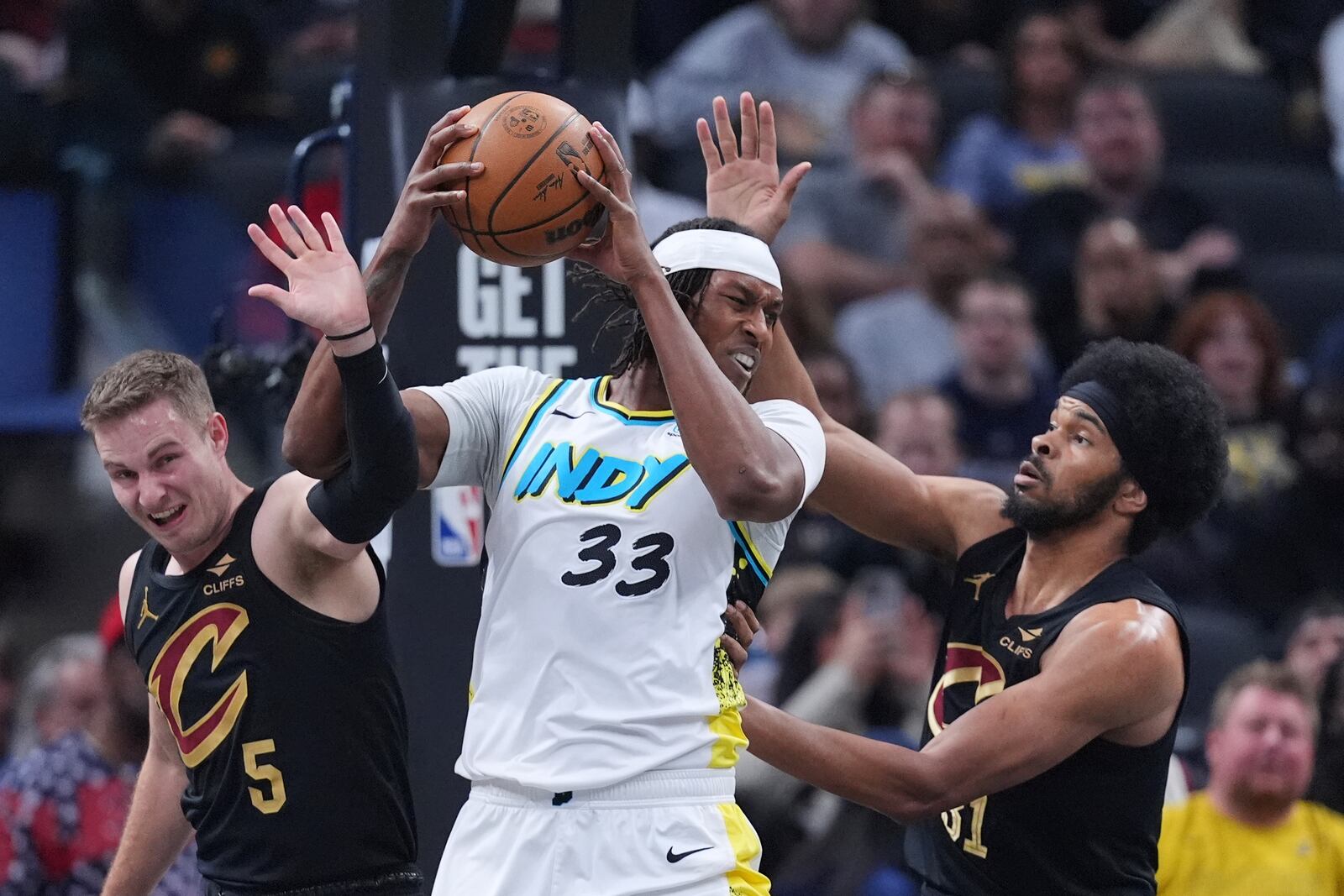 Indiana Pacers center Myles Turner (33) grabs a rebound between Cleveland Cavaliers guard Sam Merrill (5) and center Jarrett Allen (31) during the first half of an NBA basketball game in Indianapolis, Thursday, April 10, 2025. (AP Photo/Michael Conroy)