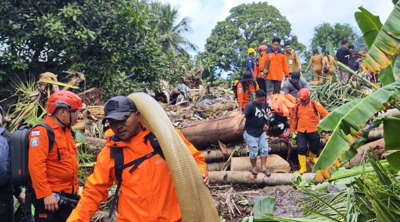 In this photo released by the Indonesian National Search and Rescue Agency (BASARNAS) on Tuesday, Jan. 6, 2026, rescuers and villagers search for victims after flash floods hit Sitaro district of North Sulawesi province, Indonesia. (BASARNAS via AP)