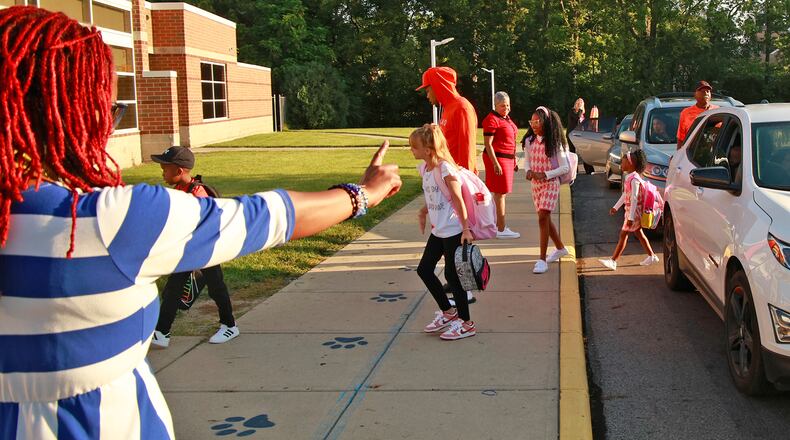 A Futon Elementary staff member directs traffic as children are dropped off for the first day of school Wednesday, August 14, 2024. BILL LACKEY/STAFF
