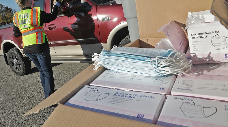 Michelle Clements-Pitstick, director of the Clark County Emergency Management Agency, passes out free COVID-19 masks at Enon Park on Nov. 13 as part of the county's efforts to slow the spread of the coronavirus. The EMA will host two free mask distribution events this week. BILL LACKEY/STAFF