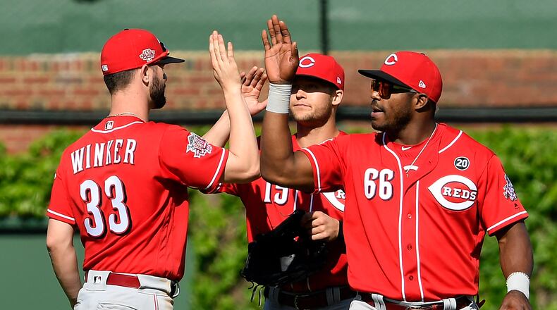 CHICAGO, ILLINOIS - MAY 26: Nick Senzel #15, Yasiel Puig #66, and Jesse Winker #33 of the Cincinnati Reds celebrate the 10-2 win against the Chicago Cubs at Wrigley Field on May 26, 2019 in Chicago, Illinois. (Photo by Quinn Harris/Getty Images)