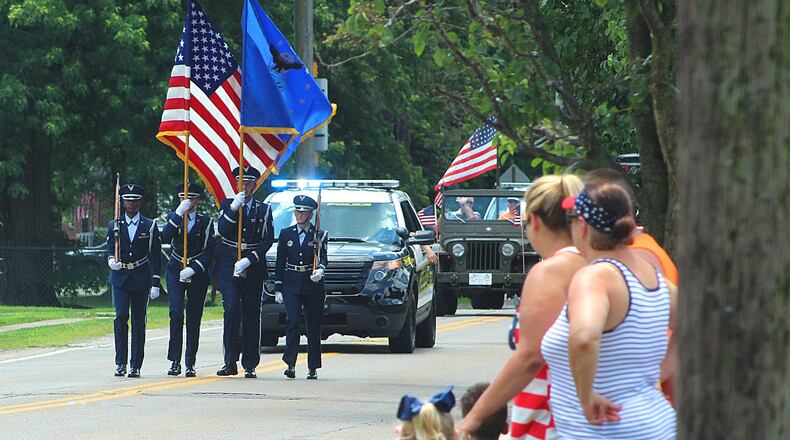 Enon Parade spectators stand as the U.S. flag is carried to start the parade. JEFF GUERINI/STAFF
