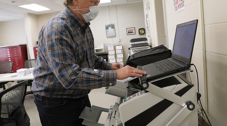 Clark County Board of Elections employee Martin Mahoney starts up one of the machines used to scan mail-in ballots at the Board of Elections last year. BILL LACKEY/STAFF