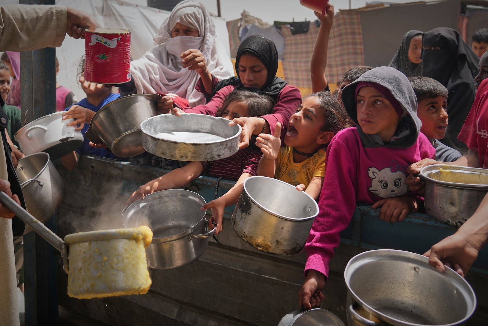 Palestinian children and women struggle to get donated food at a community kitchen in Khan Younis, southern Gaza Strip, Thursday April 24, 2025.(AP Photo/Abdel Kareem Hana)
