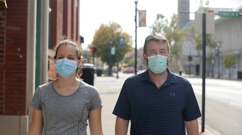 A couple wears masks as they walk along Fountain Avenue in Springfield Friday. BILL LACKEY/STAFF
