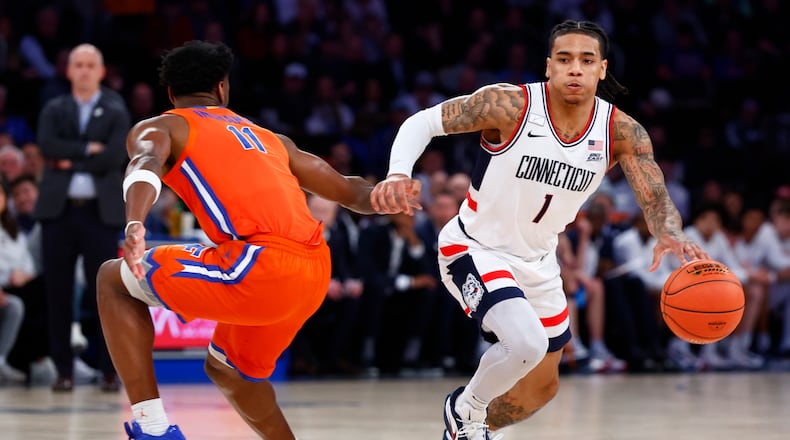 UConn guard Solo Ball (1) drives to the basket against Florida guard CJ Ingram II (11) during the first half of an NCAA basketball game, Tuesday, Dec. 9, 2025, in New York. (AP Photo/Noah K. Murray)