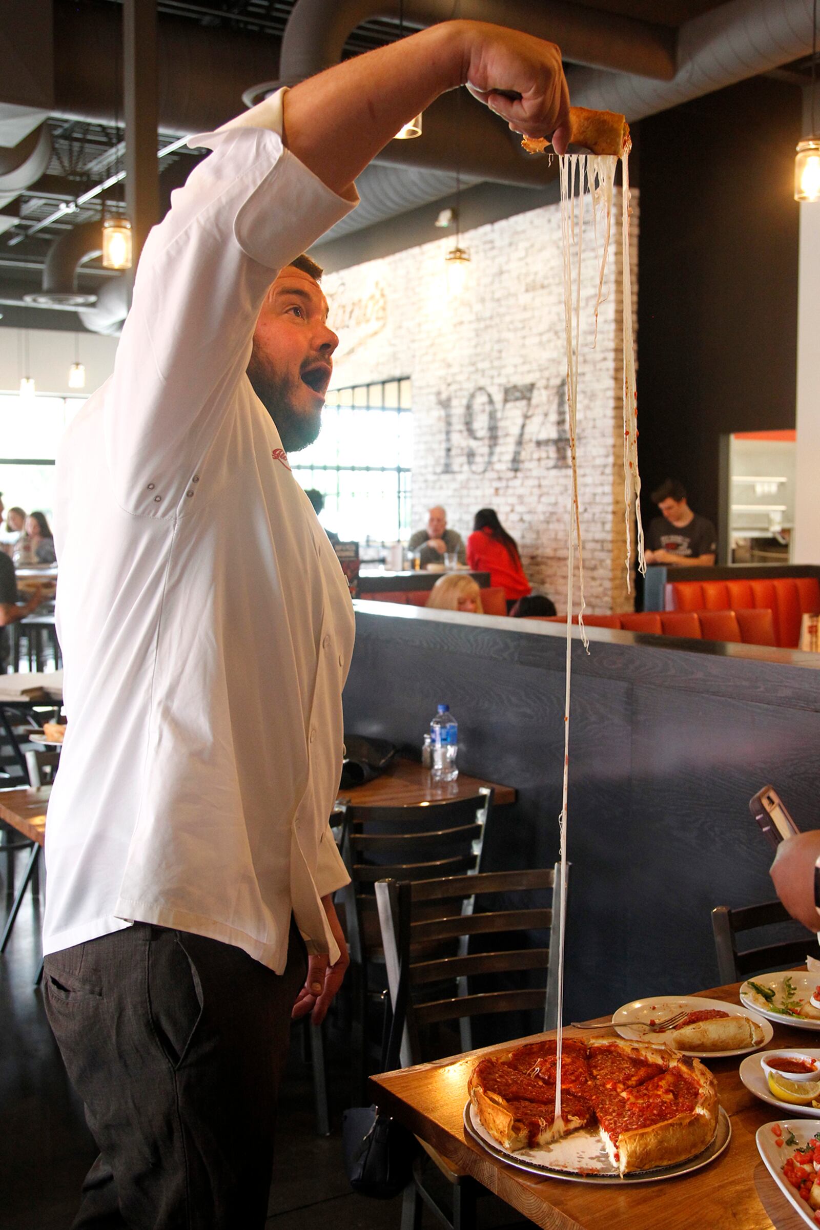Giordano's head chef Jesse Harris demonstrates how far he can pull the cheese from the restaurants famous stuffed deep dish pizza at the company's Beavercreek store. LISA POWELL / STAFF