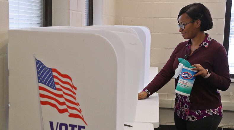 Camille Hall, from the Clark County Board of Elections, wipes down voting booths for early voters Wednesday. The Board of Elections is taking steps to make sure polling places are clean and virus free. BILL LACKEY/STAFF