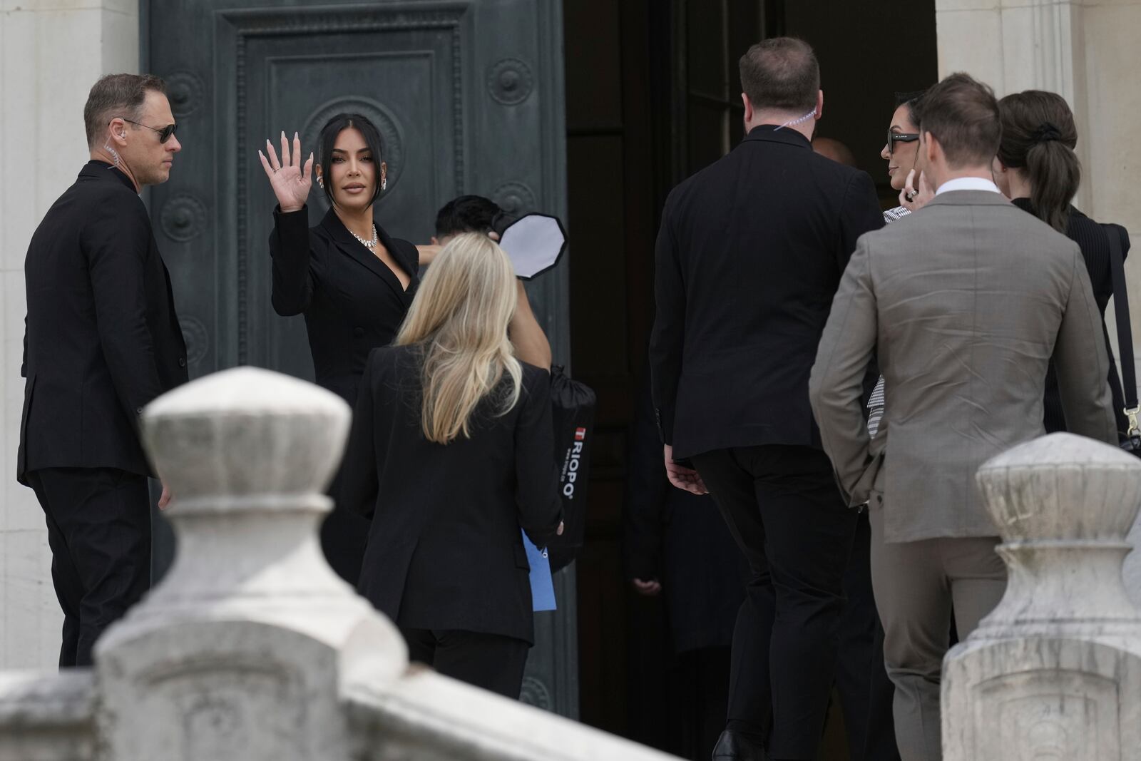 Kim Kardashian waves as she arrives to testify regarding a robbery of millions of dollars in jewels from her Paris hotel room in 2016, in Paris, Tuesday, May 13, 2025. (AP Photo/Aurelien Morissard)