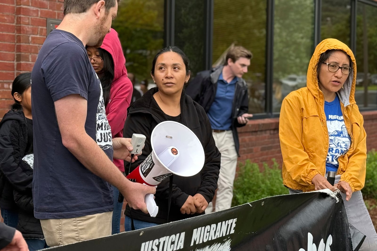 Wuendy Bernardo, foreground center, a migrant dairy farmworker at risk of deportation, is greeted by Migrant Justice staff member Will Lambek, left, outside a U.S. Immigration and Customs Enforcement office in St. Albans, Vt., on Friday, June 20, 2025. Lambek led a rally in support of Bernardo as she reported to the office for an appointment. (AP Photo/Amanda Swinhart)