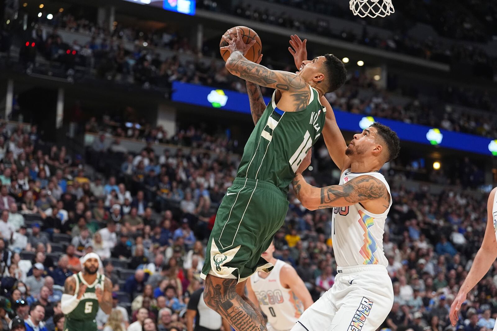 Milwaukee Bucks forward Kyle Kuzma, left, drives to the basket as Denver Nuggets forward Michael Porter Jr. defends in the first half of an NBA basketball game Wednesday, March 26, 2025, in Denver. (AP Photo/David Zalubowski)