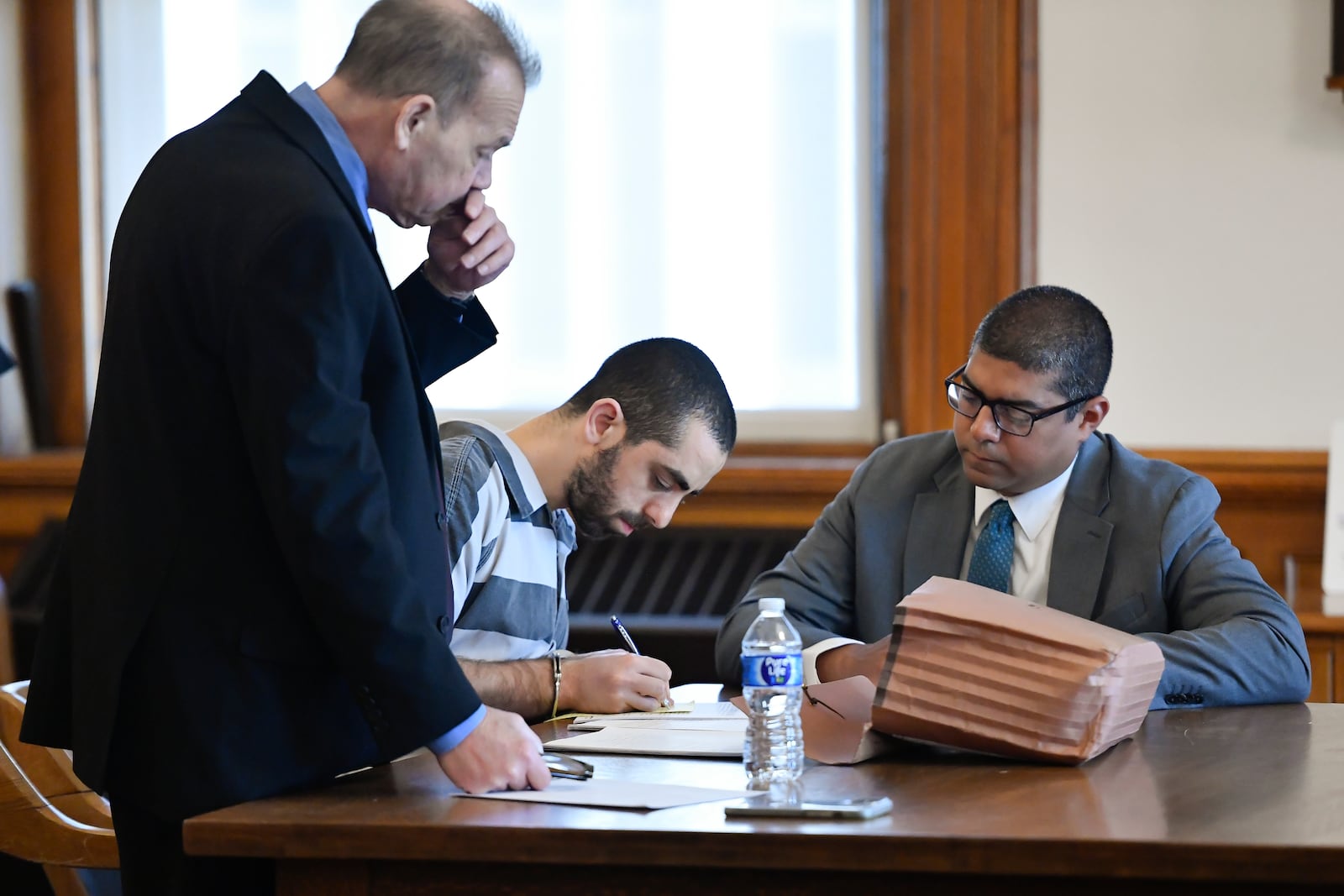 Hadi Matar, center, writes as public defender Nathaniel Barone, left, looks on in Chautauqua County court in Mayville, N.Y., Friday, May. 16, 2025. (AP Photo/Adrian Kraus)