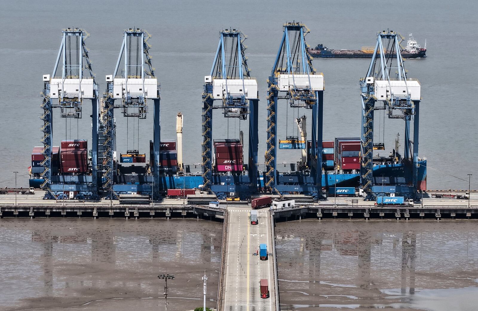 Quay cranes load containers on a ship at a container terminal in Shanghai, China on Sunday, April 27, 2025. (Chinatopix via AP)