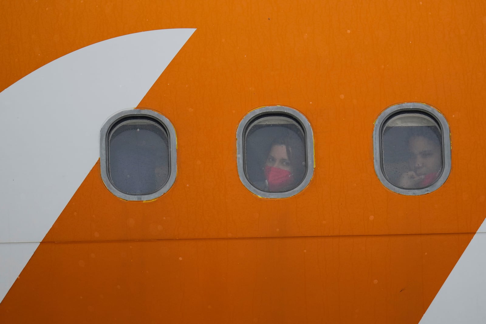 Venezuelan migrants deported from the United States look out from plane portholes upon landing at the Simon Bolivar International Airport in Maiquetia, Venezuela, Friday, May 2, 2025. (AP Photo/Ariana Cubillos)