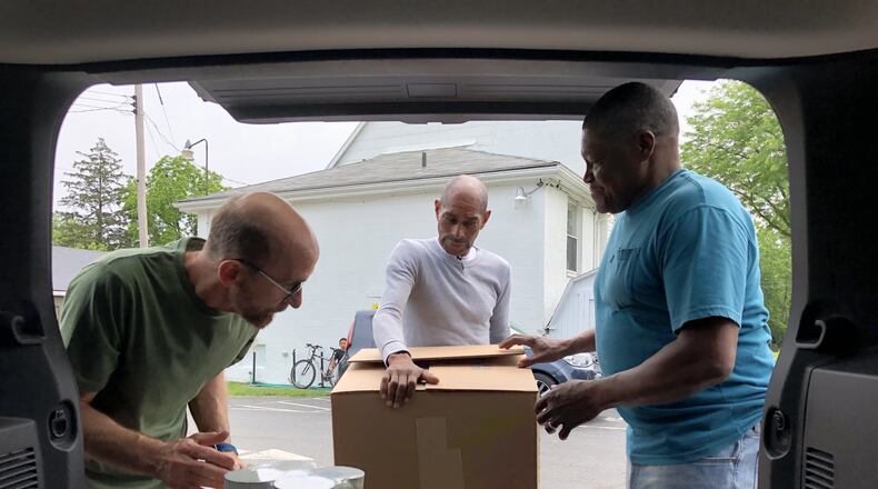 Tom Good of Abundant Life Church, left, volunteer J. Walls and Alonzo McCoy, director of the House of Prayer food pantry, unload food donations on Tuesday, June 4 at the pantry, located at 1403 S. Yellow Springs St. Photo by Brett Turner