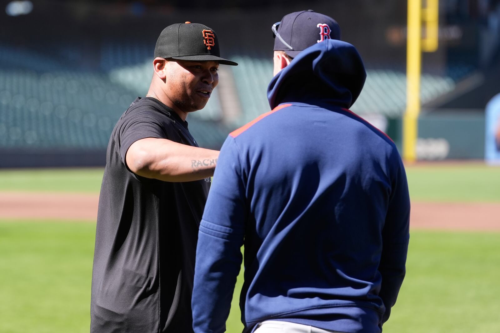 San Francisco Giants' Rafael Devers, left, talks with Boston Red Sox's Romy Gonzalez before a baseball game in San Francisco, Friday, June 20, 2025. (AP Photo/Jeff Chiu)
