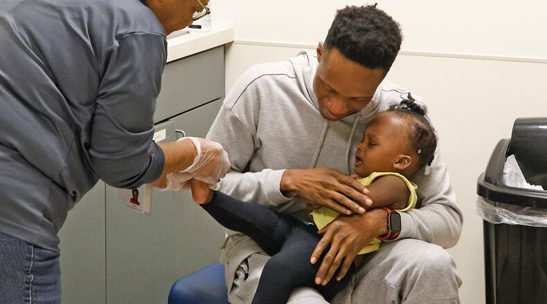 Roody Toussaint comforts his daughter, Mary Woodarline Toussaint, as nurse Susan Cole draws a drop of blood from her foot Monday, Oct. 16, 2023 at the Clark County Combined Health District's WIC program office. BILL LACKEY/STAFF