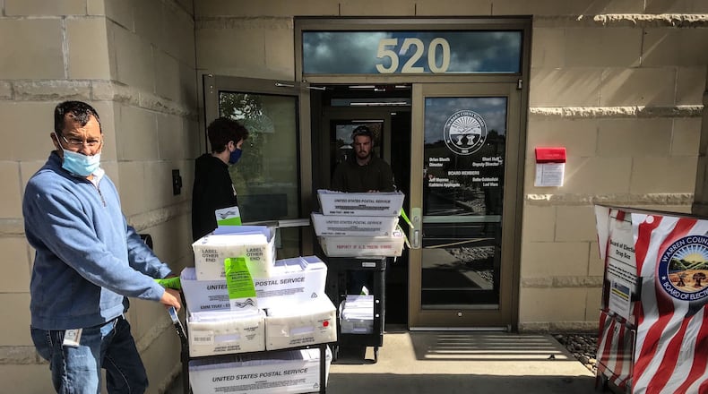 Brian Sleeth, left, Warren County Board of Elections director, wheels part of the county's more than 47,000 absentee ballots out the door. Workers on Monday took the ballots to a postal facility to be mailed Tuesday. In addition to voting absentee beginning Tuesday, registered voters can cast ballots by in-person early voting. Across Ohio, the hours this week through Friday are from 8 a.m. to 5 p.m. Twice as many Ohioans are expected to vote by mail than in 2016 because of the coronavirus pandemic. JIM NOELKER / STAFF