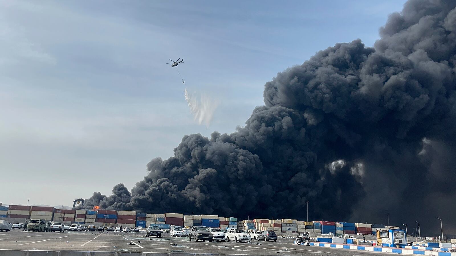 In this photo provided by Iranian Students' News Agency, ISNA, a helicopter drops water on the fire after a massive explosion rocked a port near the southern port city of Bandar Abbas, Iran, Saturday, April 26, 2025. (Razieh Pudat/ISNA via AP)
