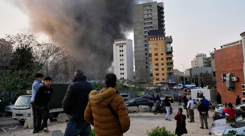 Residents watch as smoke rises from a nearby building during an Israeli strike in central Beirut, Lebanon, Thursday, March 12, 2026. (AP Photo/Hussein Malla)