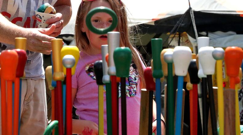 Lillian Bias, 5, watches as her father tries to win her a colorful can Friday during the opening day of the Champaign County Fair in Urbana. This year marks 127th year that the Dearwester Canes game has been at the fair. BILL LACKEY/STAFF