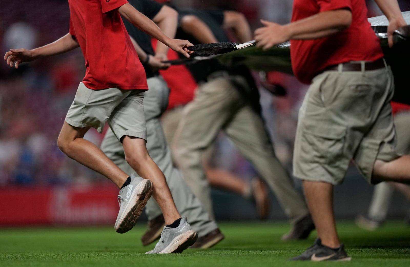 Members of he grounds crew pull the tarp over the field during a rain delay after the sixth inning of a baseball game between the Cincinnati Reds and the Philadelphia Phillies Tuesday, Aug. 12, 2025, in Cincinnati. (AP Photo/Carolyn Kaster)