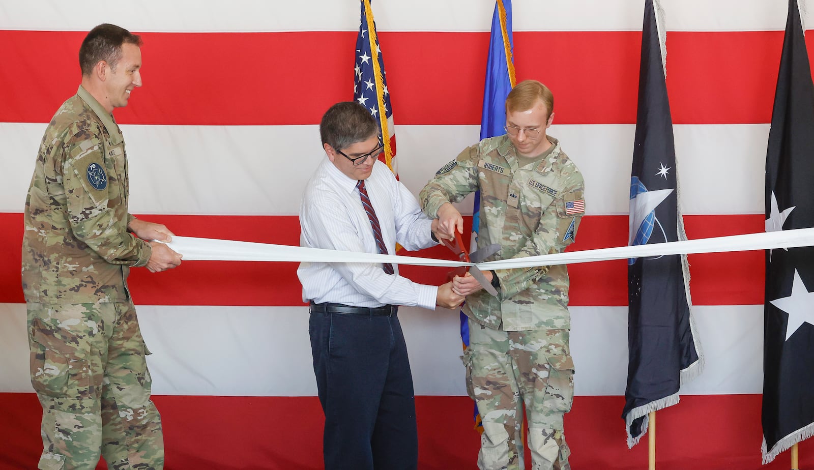 David Oue, center, and U.S. Space Force specialist Adam Roberts cut a ribbon during a ceremony for the opening of a new U.S. Space Force Combined Intelligence Operations floor, the Space Intelligence Production Cell, on Friday, September 26, 2025, in Springfield. JOSEPH COOKE/STAFF