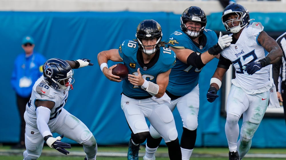 Jacksonville Jaguars quarterback Trevor Lawrence (16) runs the ball past Tennessee Titans outside linebackers Truman Jones (56) and Jaylen Harrell, far right, during the second half of an NFL football game Sunday, Jan. 4, 2026, in Jacksonville, Fla. (AP Photo/John Raoux)