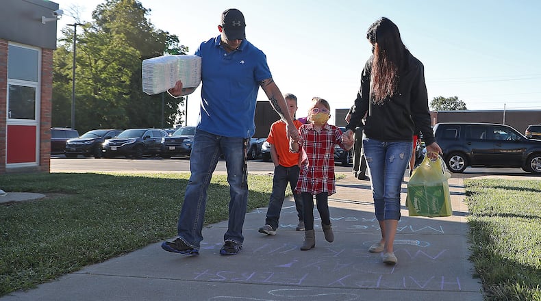 A family walks into Triad Elementary School Thursday for the first day of class on Aug. 19, 2020. Under new requirements from Gov. Mike DeWine, parents and staff will be required to report coronavirus cases to their school districts. Triad Local Local Schools has not reported any school related cases. BILL LACKEY/STAFF
