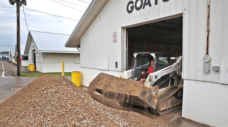 A work crew at the Clark County Fairgrounds puts down new gravel for the floor of the Goat Barn Friday as they get ready for the upcoming fair. BILL LACKEY/STAFF