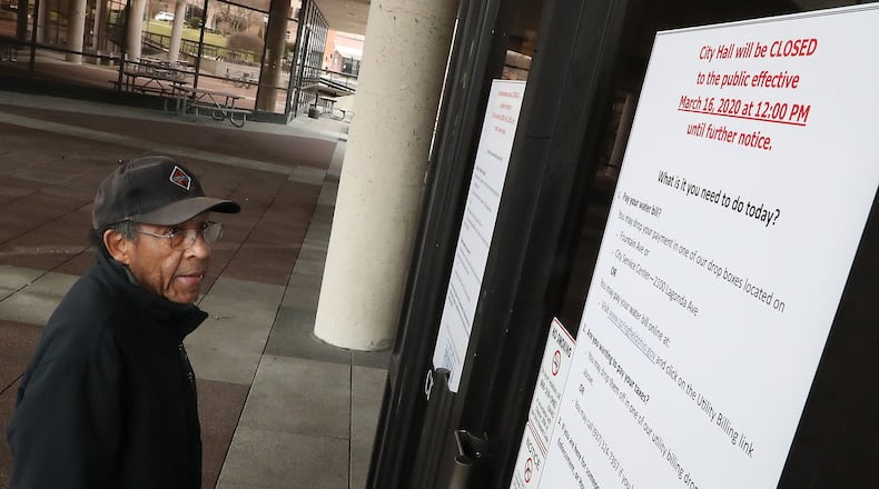 Lewis Hill reads the “Closed” sign on the doors at the Springfield City Hall Monday. Hill said he had come down to City Hall to pay his water bill but was directed to go to a drop box. The City of Springfield offices closed Monday at 12pm due to the health crisis. BILL LACKEY/STAFF