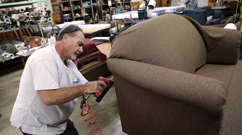 Richard Donaldson upholsters a love seat in the Jim Miller Furniture workshop Wednesday at their new location at 2960 Dayton Road. BILL LACKEY/STAFF