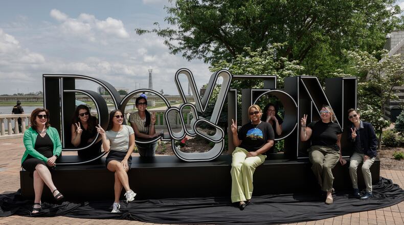 A group takes a photo at the newly unveiled Dayton Peace Sign on Thursday, May 15, 2025, at RiverScape MetroPark Festival Plaza. JOSEPH COOKE/STAFF
