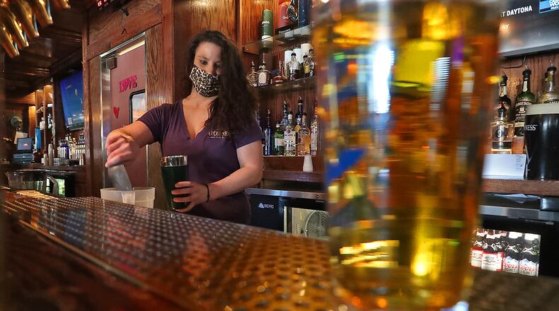 Nicki Callicoat makes a drink at O'Conner's Irish Pub as she tends bar Friday. BILL LACKEY/STAFF