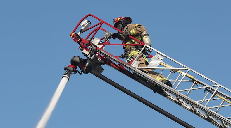 A Springfield Fire Division firefighter hoses down flames of a structure fire. BILL LACKEY/STAFF