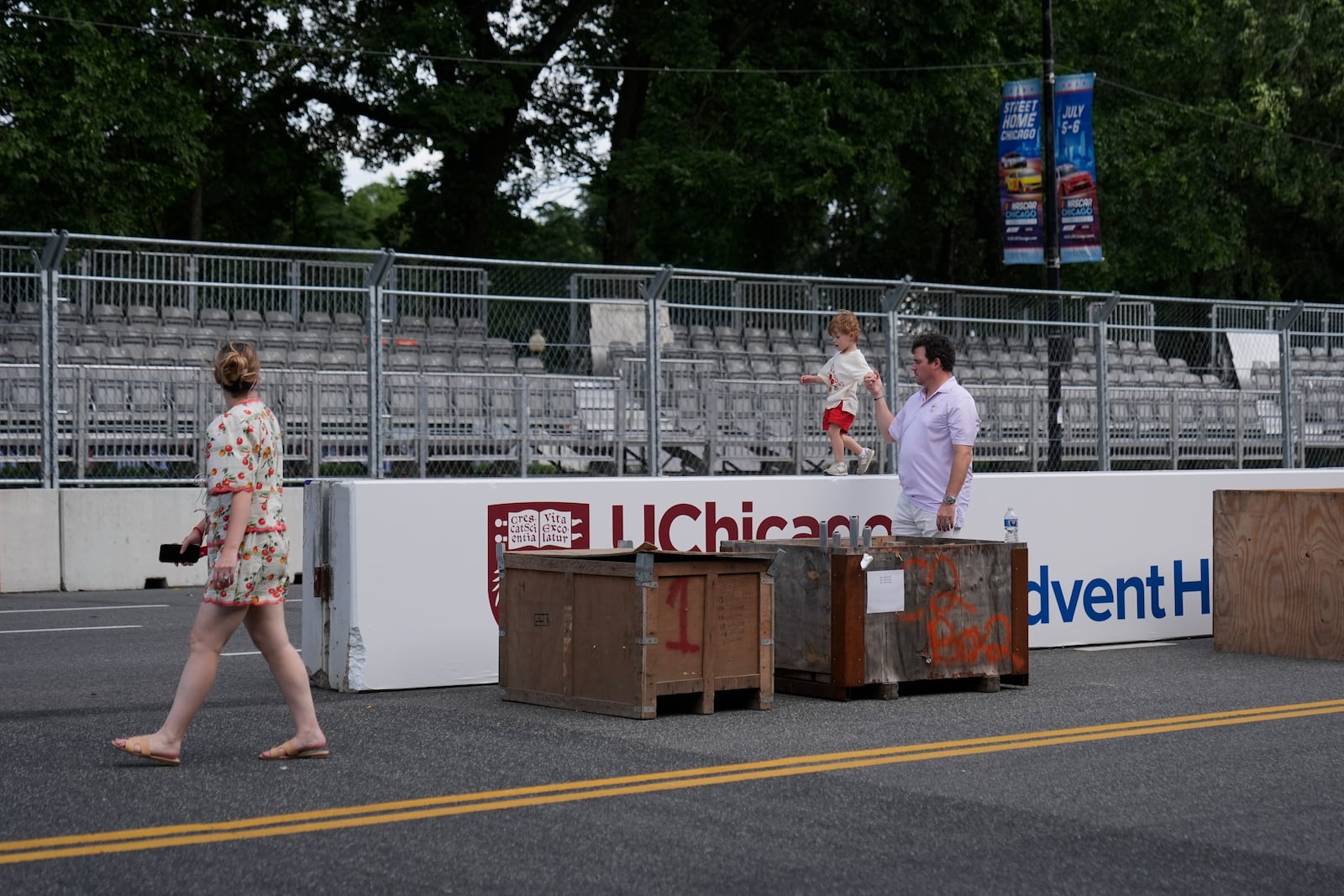 People walk by as construction of the street course continues ahead of the NASCAR auto racs, Friday, June 27, 2025, in downtown Chicago. (AP Photo/Erin Hooley)